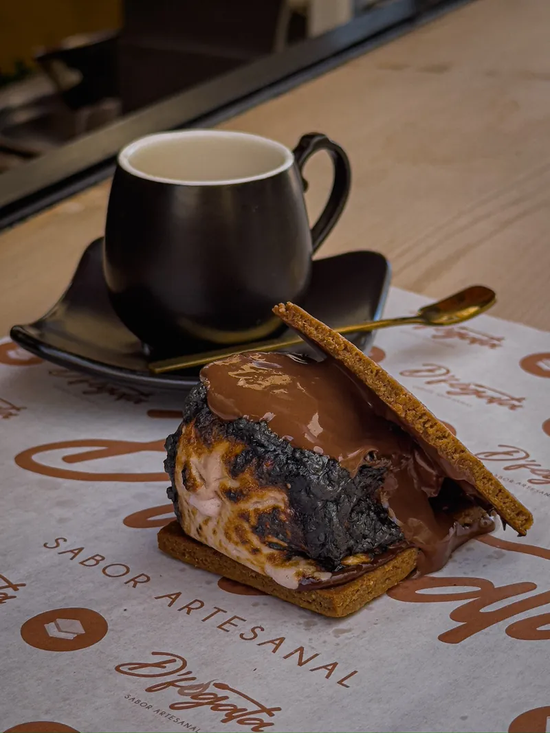 S’more con malvavisco asado y chocolate, junto a un café